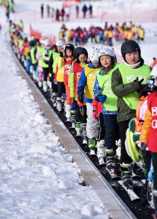 在吉林北大壺滑雪場，吉林市第二實驗小學學生們在滑雪教練的帶領下乘坐“魔毯”前往雪場學習區域。
